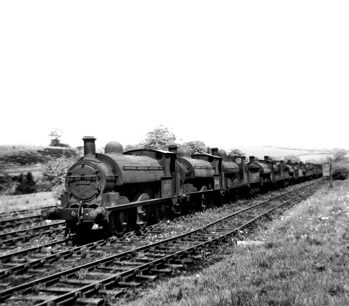 The sight that greeted us as we entered the Royal Ordnance Factory sidings at Heapey on May 16, 1959 – 15-old-steam locomotives dumped in the countryside unwanted and with nowhere to go. Left to right are: Nos. 51512, 51423, 52216, 51415, 52268, 51457, 50647, 51404, 52237, 43890, 51546, 50712, 43984, 51316 and 40178. Most, if not all, will have been to Horwich Works first where they will have been formally condemned before being towed out to Heapey in varying stages of incapacitation to await disposal. The leading four locomotives were among the first to be sent to Heapey. No. 51512 was ex-Gorton from where it had been withdrawn in July 1958. Built by Beyer Peacock in February 1882 it was one of the 0-6-0 tender engines to be converted in January 1899 to a saddle tank. It eventually departed for the Central Wagon Co at Ince near Wigan, possibly being the first BR loco to go there. 