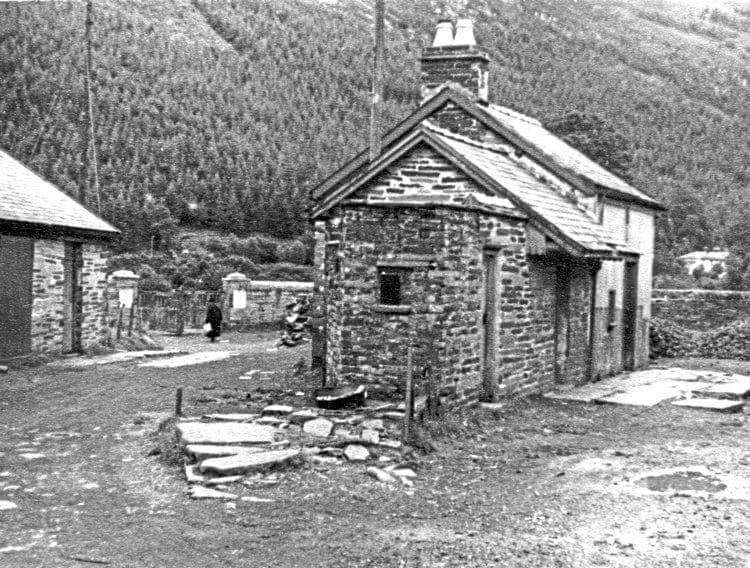 The partly demolished remains of Corris Station, August 30 1950, two years after the railway closed. The station’s storm-damaged overall roof had been removed soon after closure. The slate slabs to the right of the buildings are the remains of the passenger platform that sat beneath the roof; those in front of the building were a crude stop block for the siding that once ended here and was connected to the passing loop to the left of the main building. For a few years these sad remains were used by the local coal merchant – piles of coal can be seen on the site of the carriage shed. The station buildings were finally demolished in the summer of 1968, but the railway’s former stables, on the left, now form the small but excellent Corris Railway Museum. 