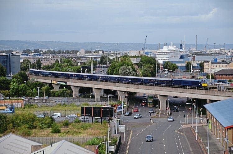 On September 10, dedicated Belmond locomotive No. 216 hauls its train of 10 Mk.3s across the Dargan Bridge en route from Belfast York Road depot to Central station, and is about to cross the River Lagan. On each visit to Belfast, the 'Grand Hibernian' runs empty stock to the depot to run round. The cruise ships in the background are the Silver Whisper (nearest the camera) and the Saga Pearl II. Chris Playfair