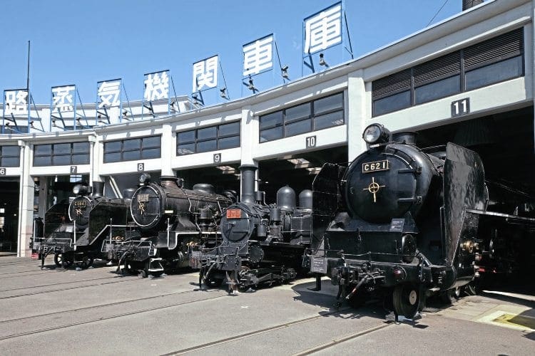 Four locos outside the historic Umekoji roundhouse. From right to left: powerful 4-6-4 C62 1, built by Hitachi in 1948, and 4-4-2T Number 1080, built in Scotland by Dubs in 1901 as a 4-4-0 tender loco (rebuilt in 1926 to the current 4-4-2T design). Nearer the camera are two Kawasaki-built locos, 2-8-0 9633 (right), dating from 1914, and (left) 1935 vintage 2-6-4T C11 64. Between 1932 and 1947, 381 C11s were built. Fifty have been preserved, including five that are currently in working order. JAMES WAITE